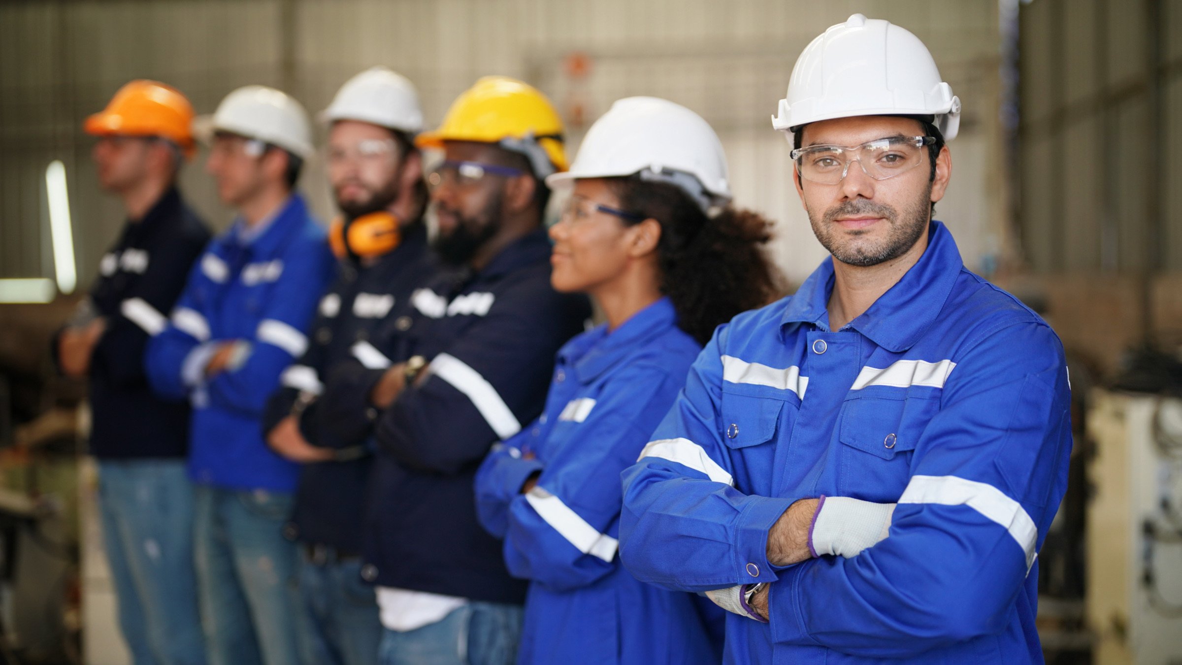 Manufacturing workers in hard hats standing together on the manufacturing plant floor
