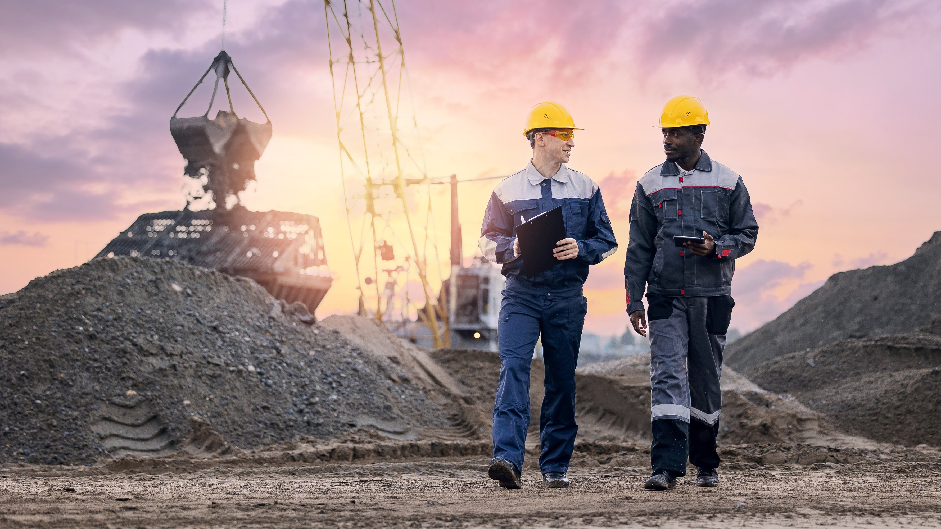 Mining heavy equipment workers wearing protective uniforms using tablets on mining port
