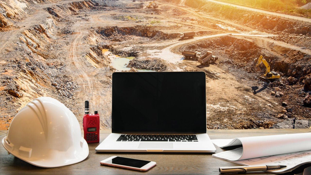 Set of mining work objects on a desk in front of an open pit mine