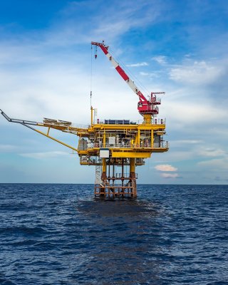 Offshore oil and gas wellhead remote platform with sea and blue sky background. Which produce raw gases and crude then sent to central processing facility far away. Oil and gas industry.