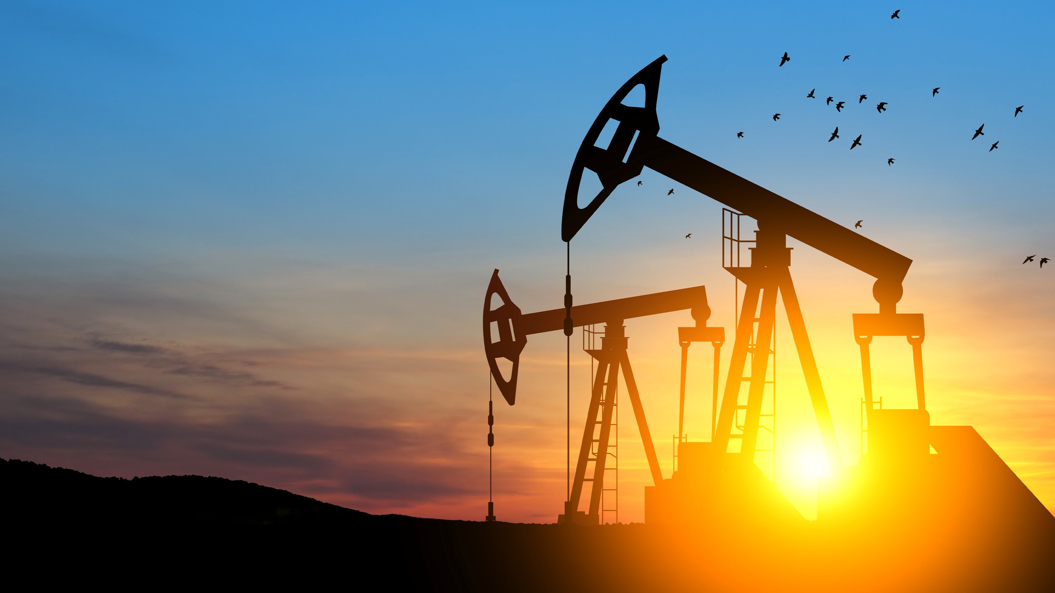 oil-drilling-derricks-at-desert-oilfield-with-sunset