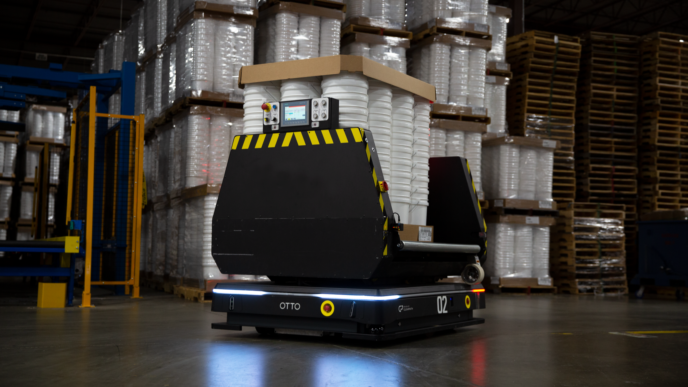 An OTTO 1500 AMR carrying stacks of white material while moving down a warehouse aisle.