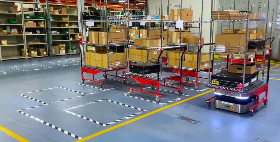 Two OTTO 600 AMRs with carrying shelves in a warehousing production logistics application.
