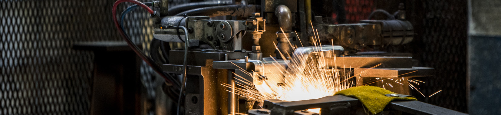 manufacturing facility interior with machinery and sparks flying from metalwork