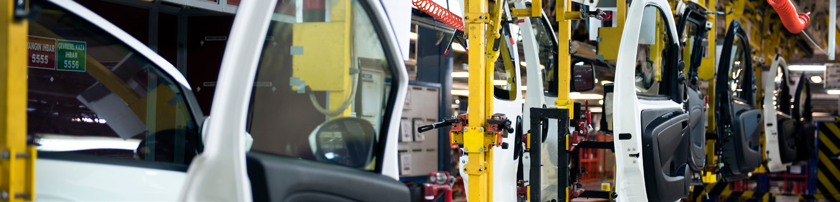 manufacturing facility interior photo with automotive assembly line and vehicle doors in yellow and white