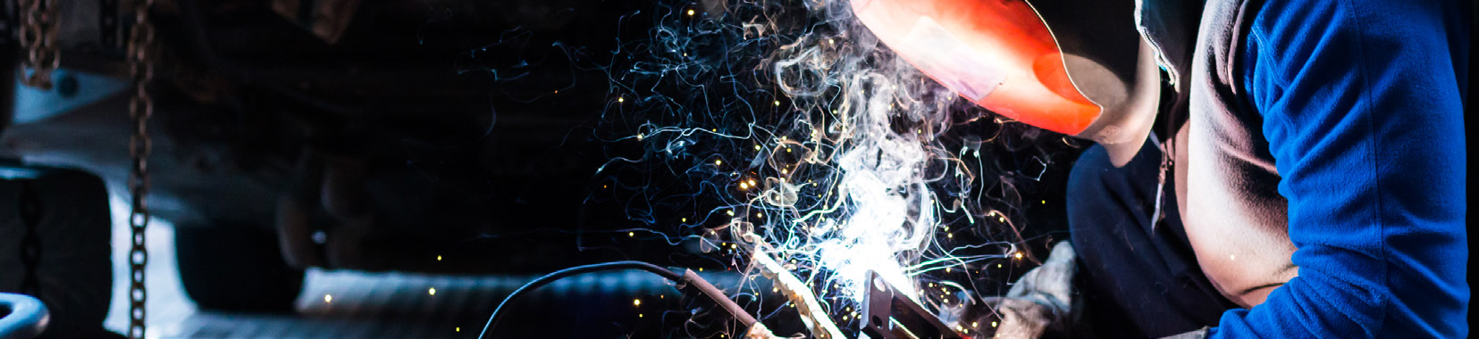 worker operating manufacturing equipment with sparks flying in a factory interior