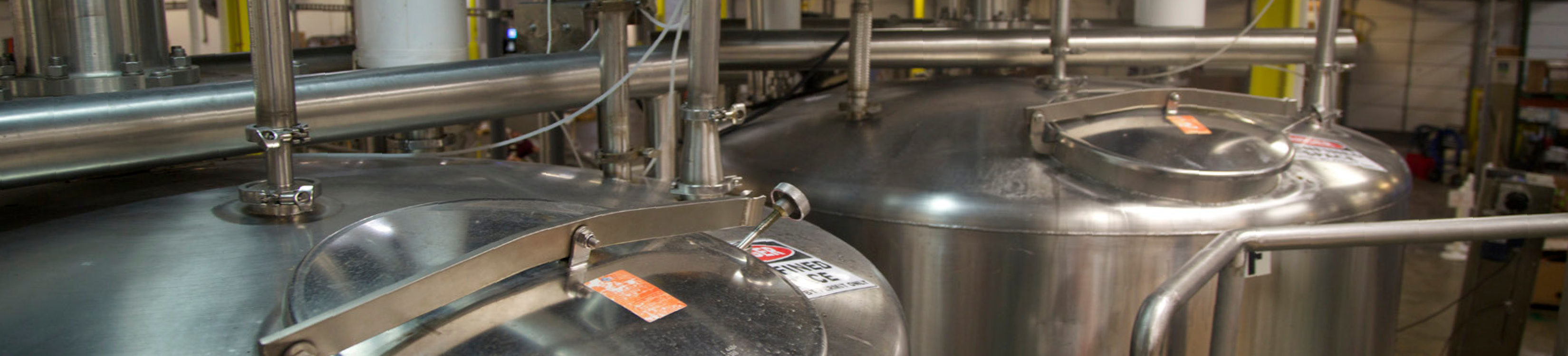 manufacturing facility interior with large stainless steel tanks and piping