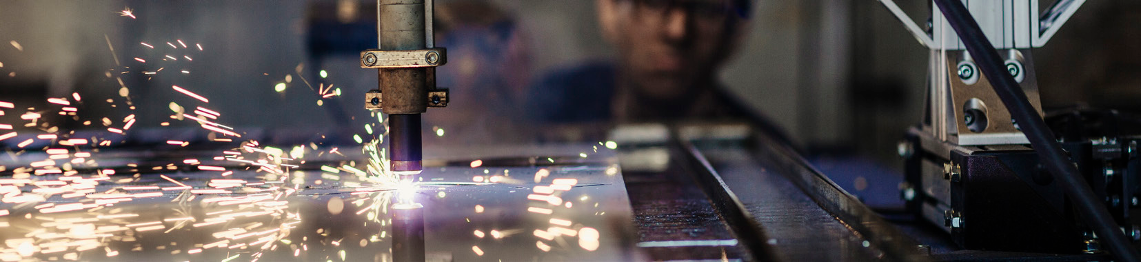 manufacturing facility interior with sparks flying from metal cutting machine