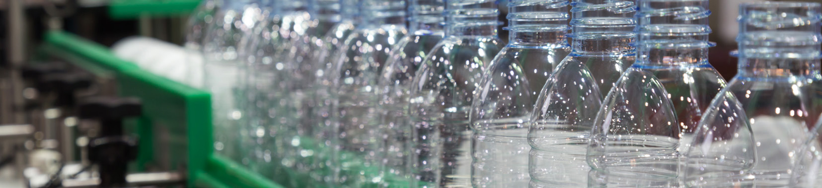 manufacturing facility interior with rows of clear plastic bottles on conveyor belt