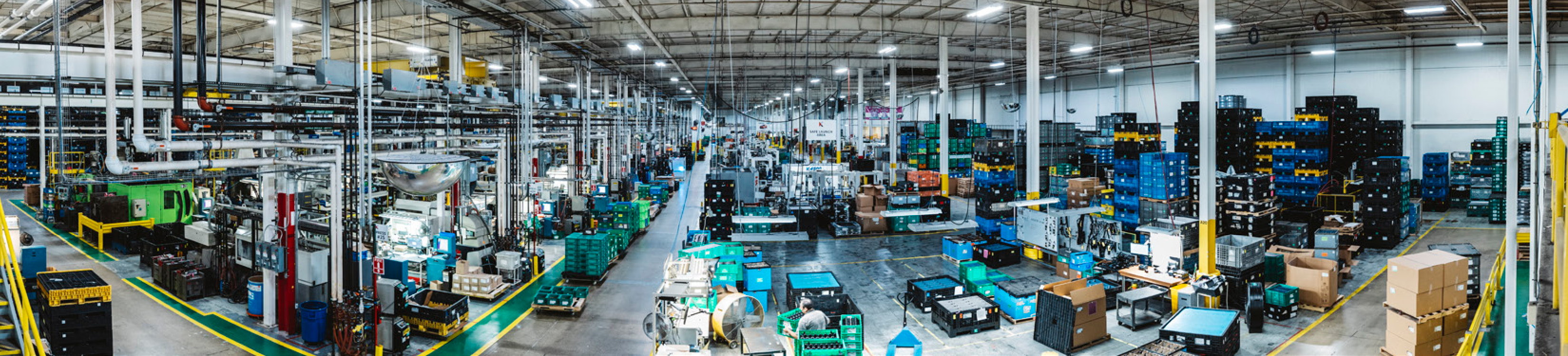 manufacturing facility interior photo showing a large factory floor with machinery, equipment, and storage bins