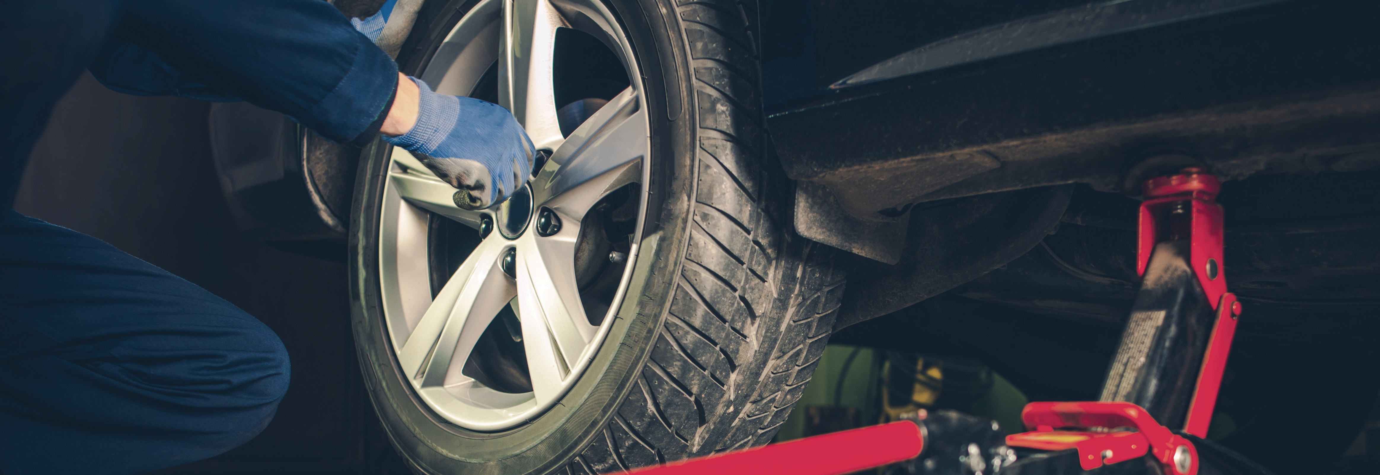 worker adjusting tire on vehicle in manufacturing facility