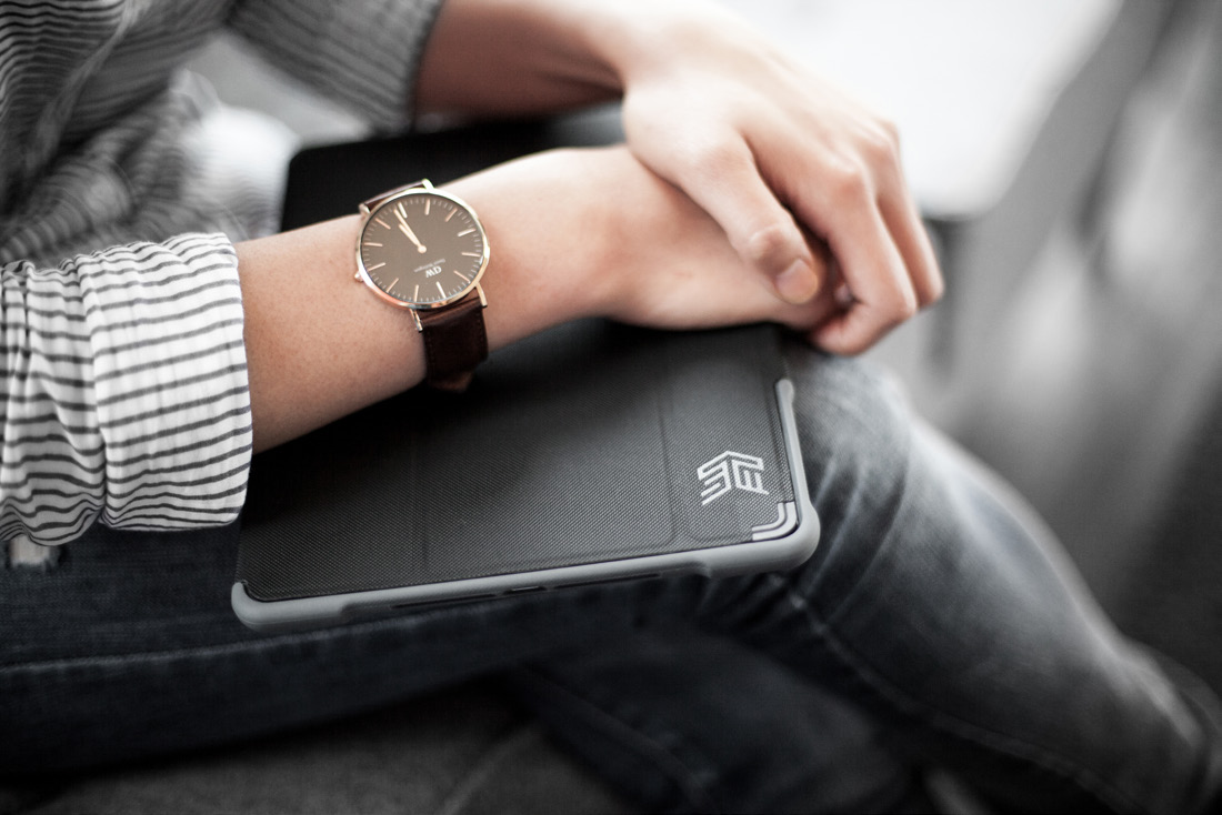 Close-up photo of a person wearing a watch and holding a black STM-branded tablet on their lap