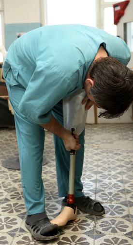 elderly woman in white lab coat and blue gloves packing boxes in a manufacturing facility