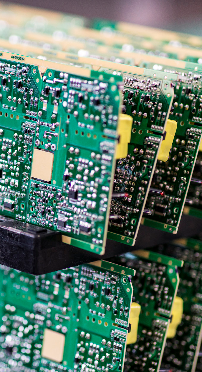 close-up photo of green printed circuit boards stacked vertically in a manufacturing environment
