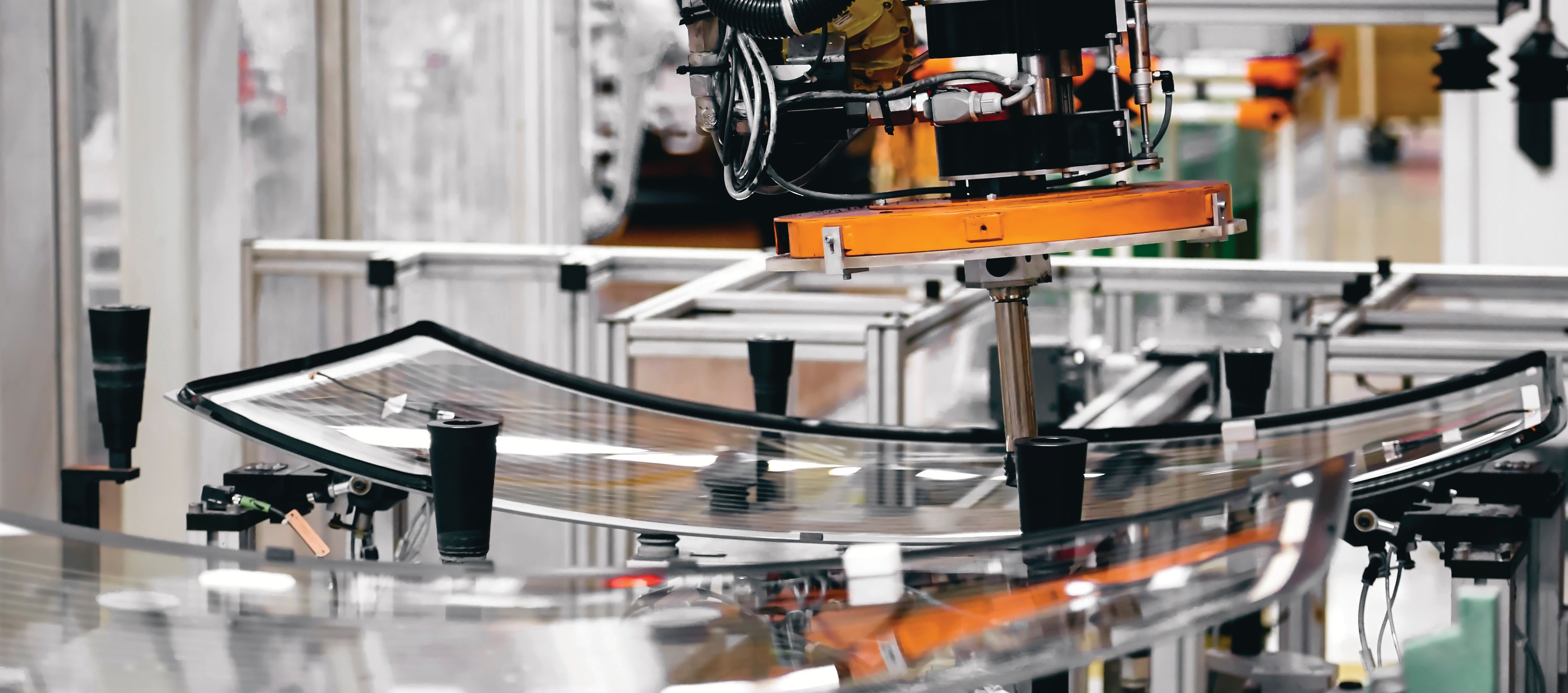 manufacturing facility interior photo with robotic arm and conveyor belts, predominantly gray and orange colors