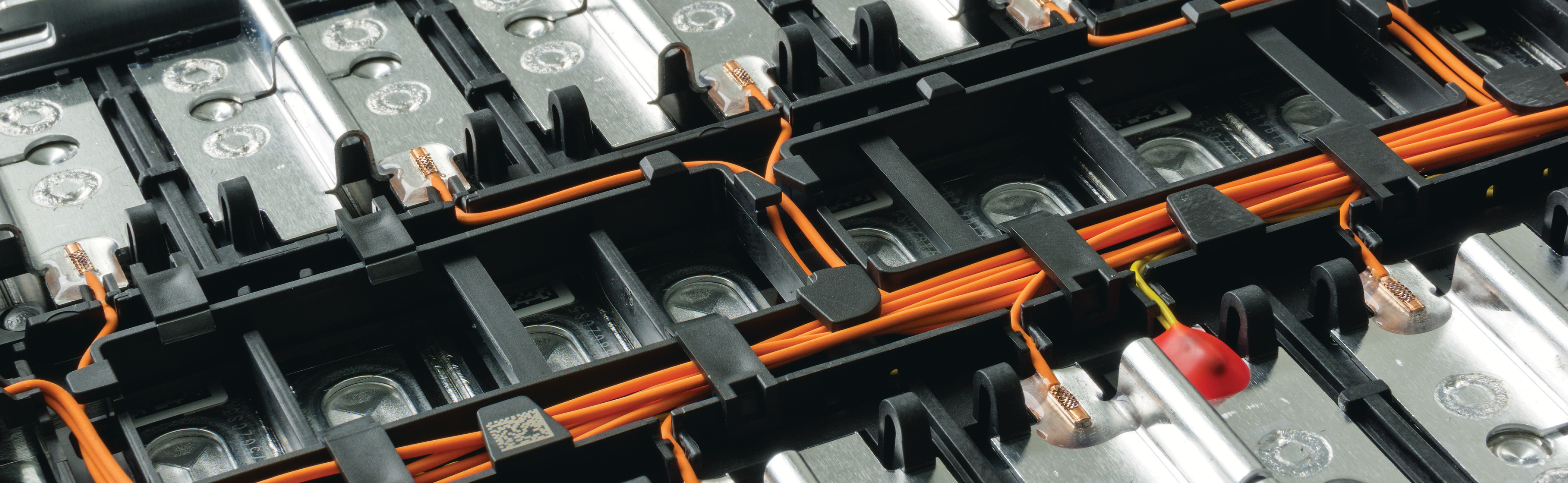 close-up photo of electric vehicle battery cells with orange wiring and metal connectors