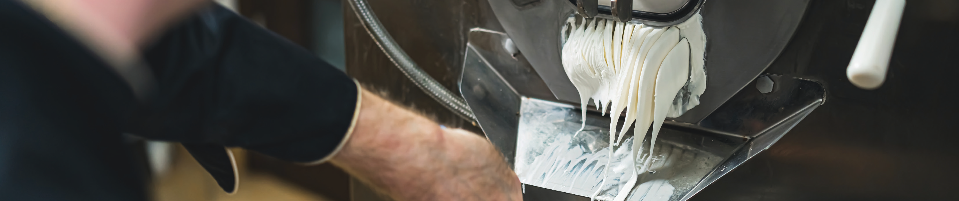 close-up photo of a chocolate production machine with white chocolate dripping