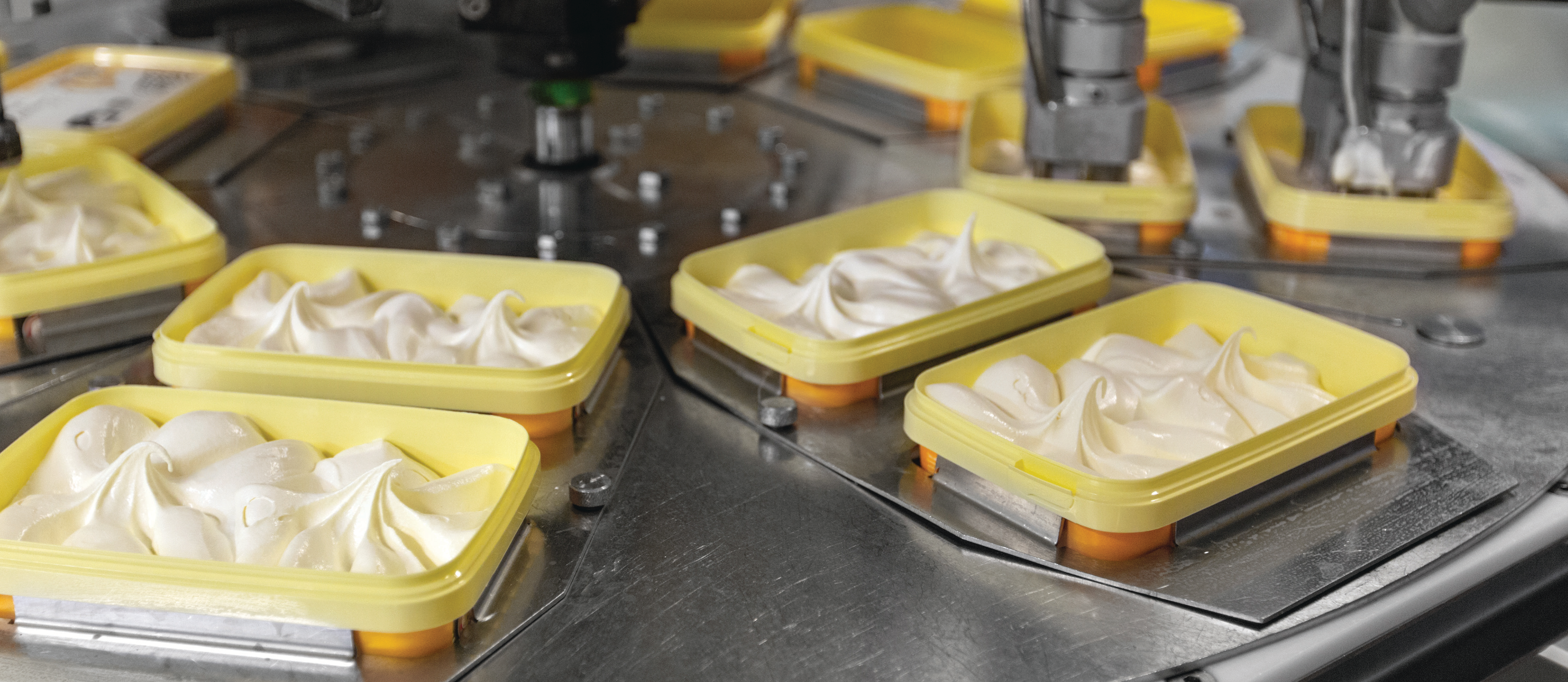 production line with yellow trays filled with ice cream in a manufacturing facility