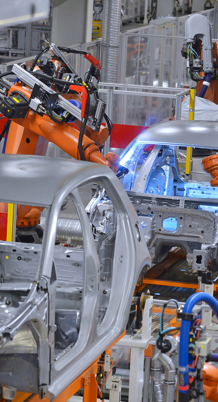 manufacturing facility interior with robotic arms assembling vehicle bodies