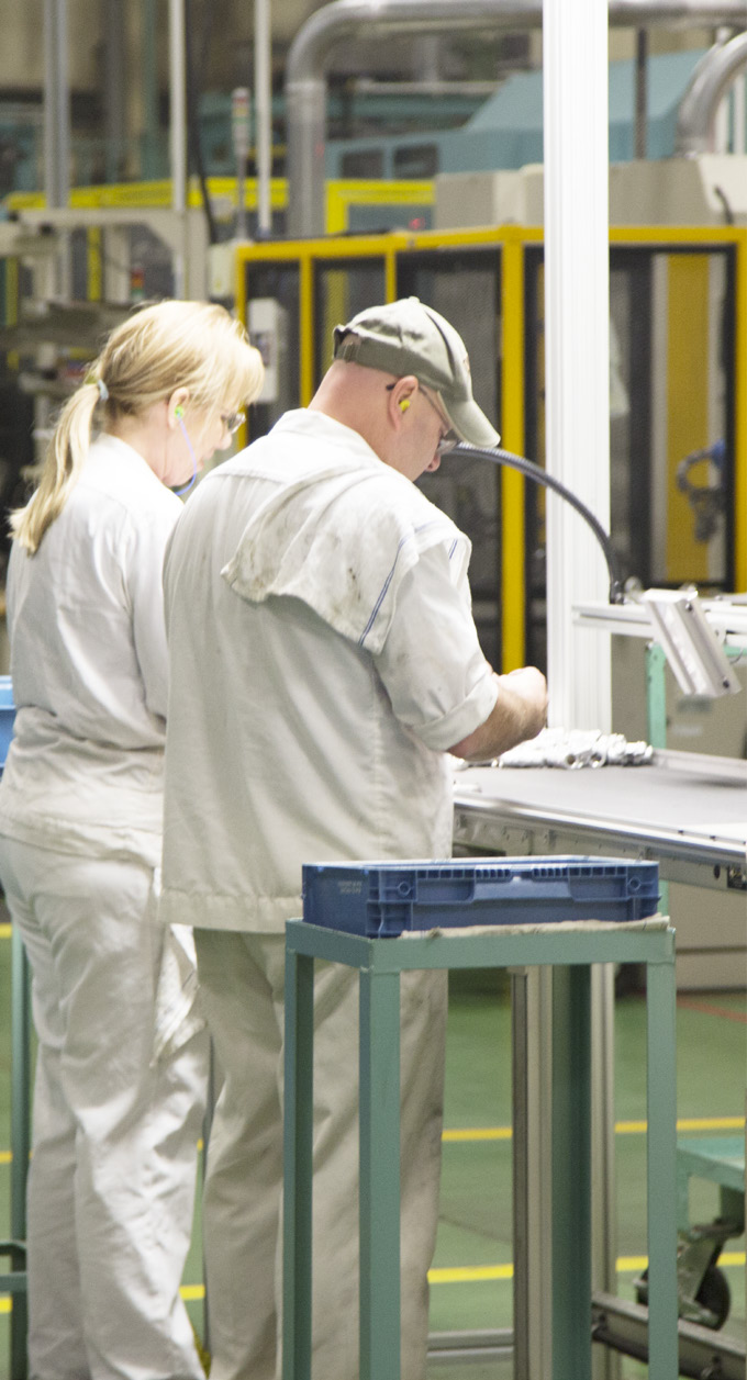 Two workers operating production line in a brightly lit manufacturing facility