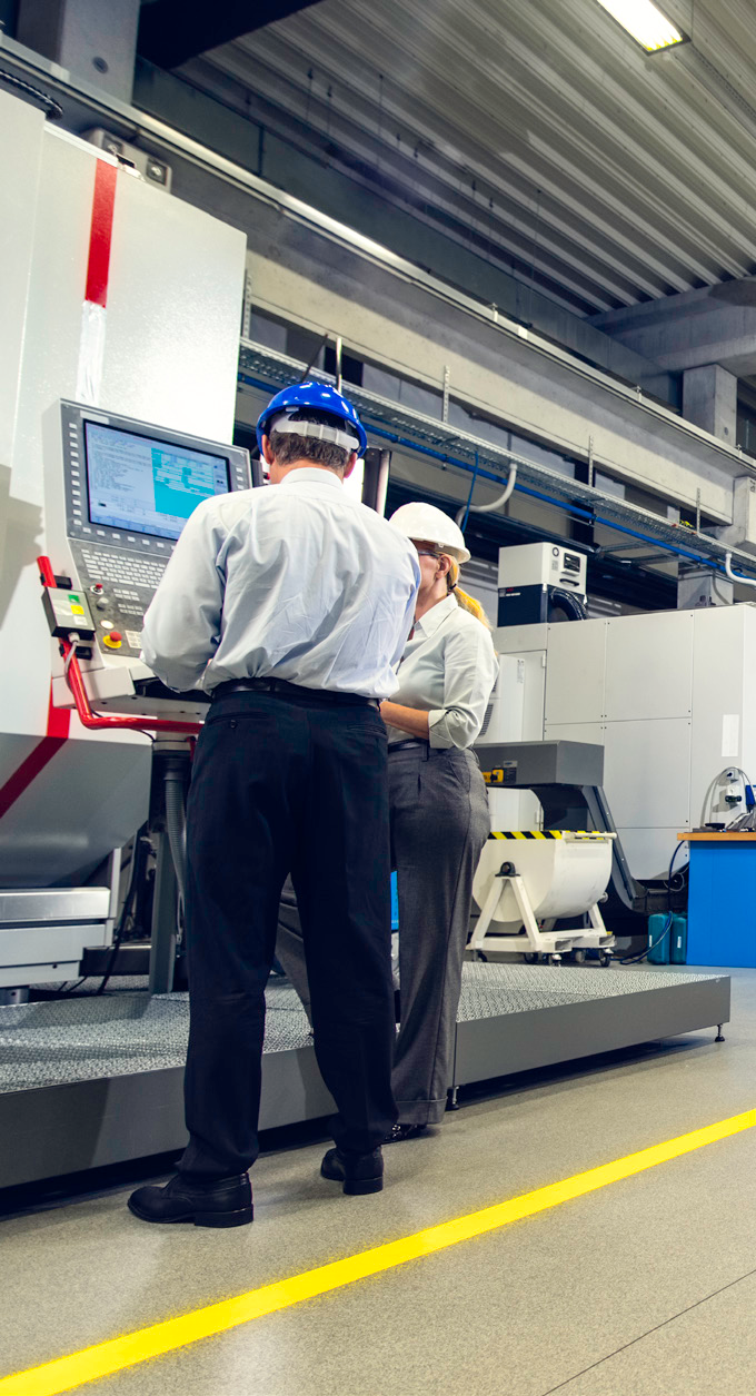 Two workers operating a production line in a brightly lit manufacturing facility