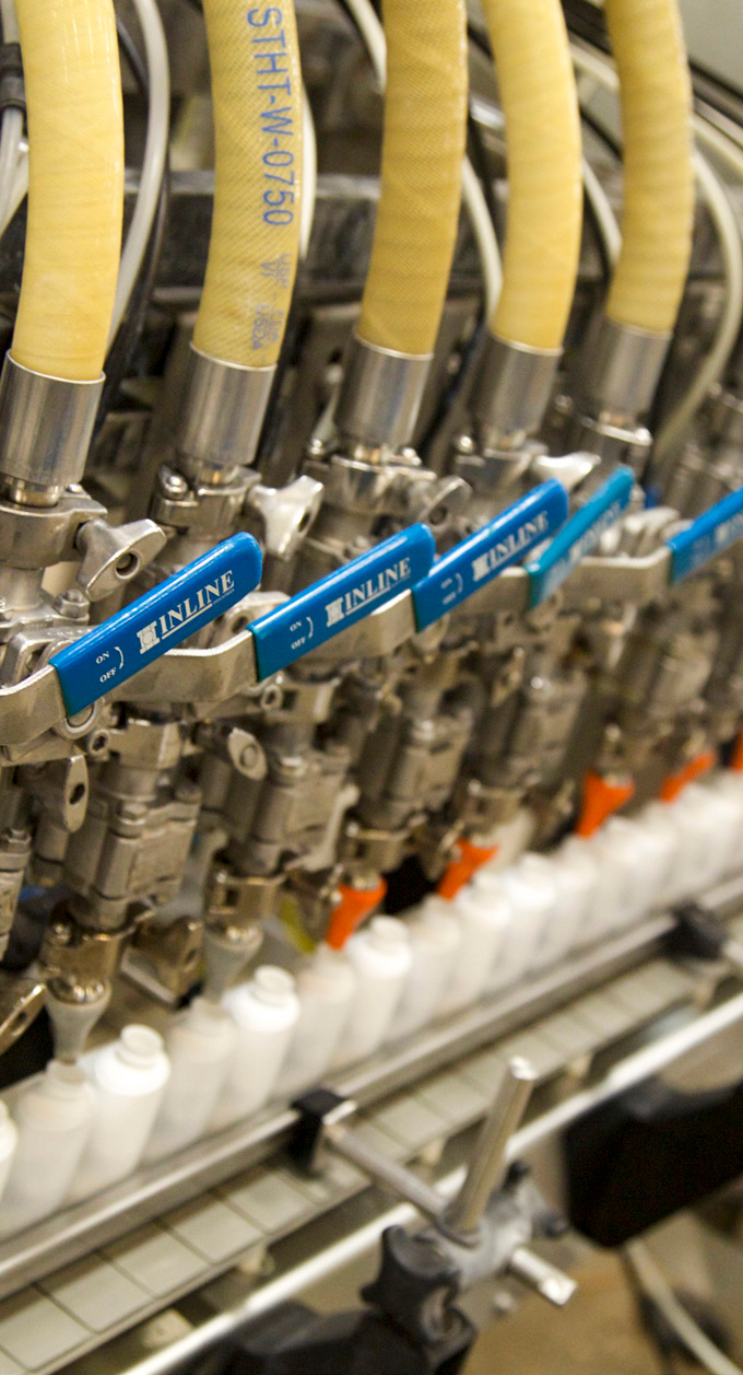close-up photo of industrial piping and valves with yellow insulation and blue labels in a manufacturing facility