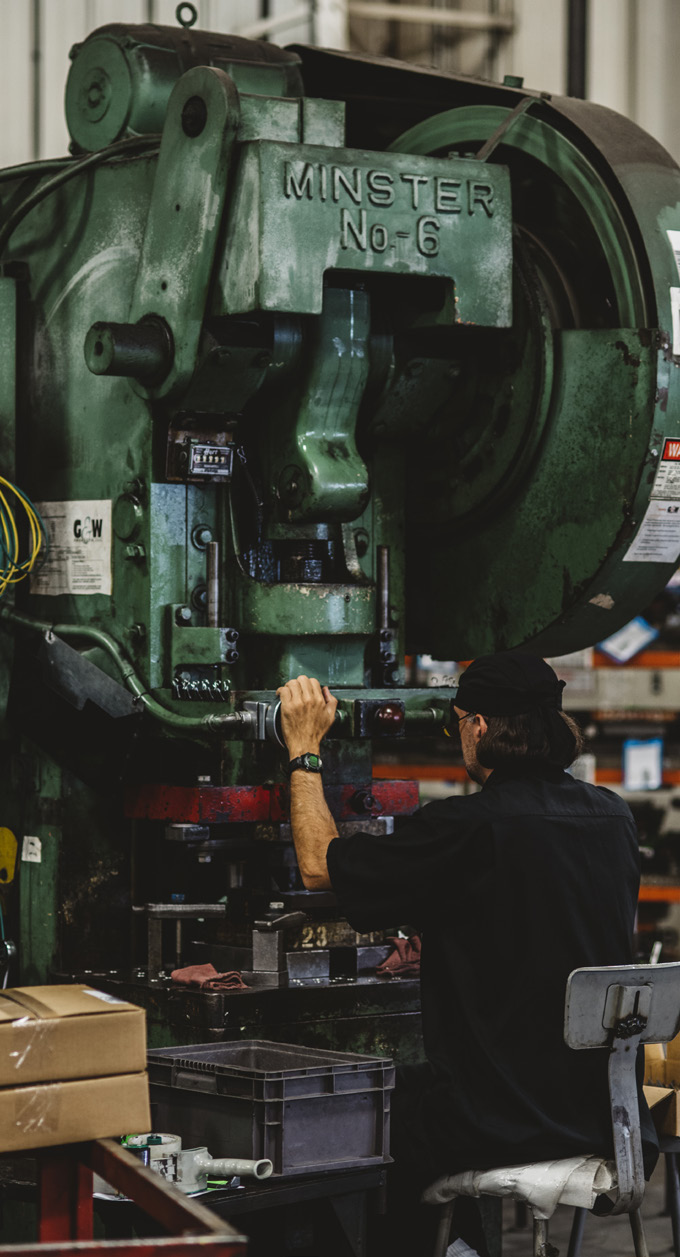 Worker operating a large green industrial machine in a manufacturing facility