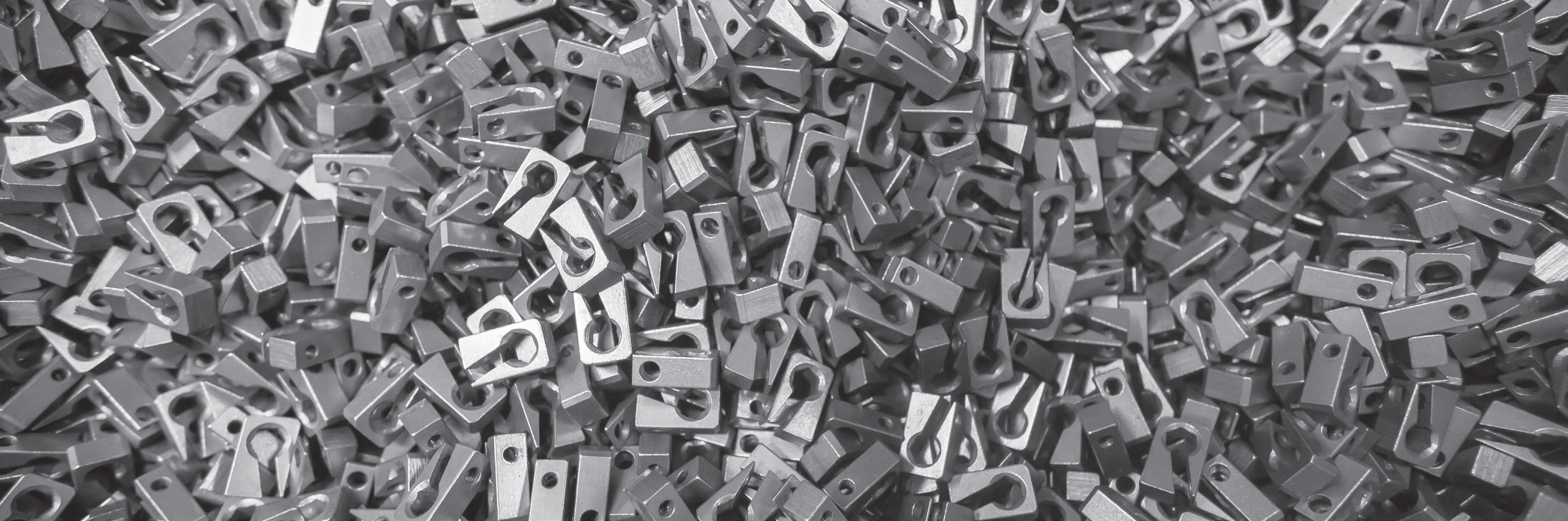 close-up photo of numerous small metal parts with holes, piled together