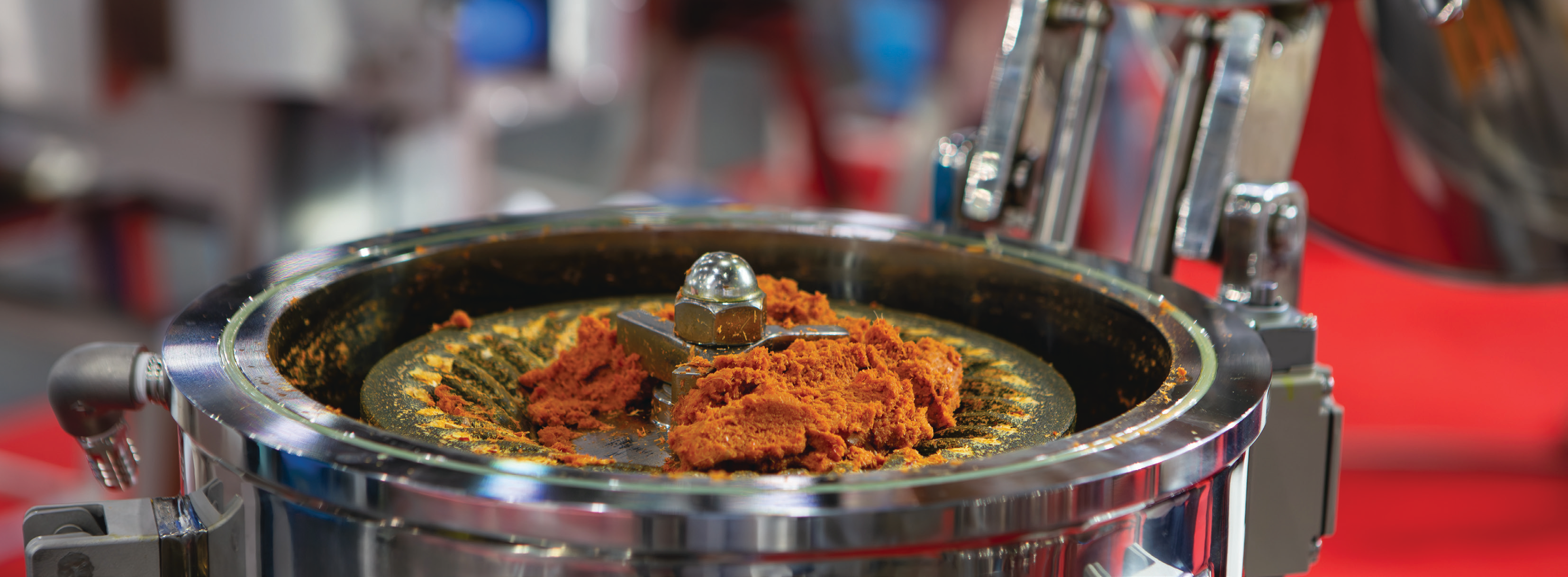 close-up photo of orange spice powder in a stainless steel grinder in a manufacturing facility
