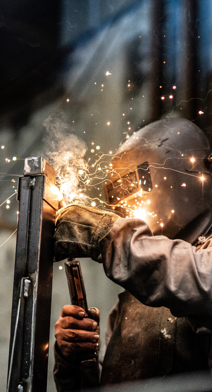 Worker operating welding equipment with sparks flying in a manufacturing facility