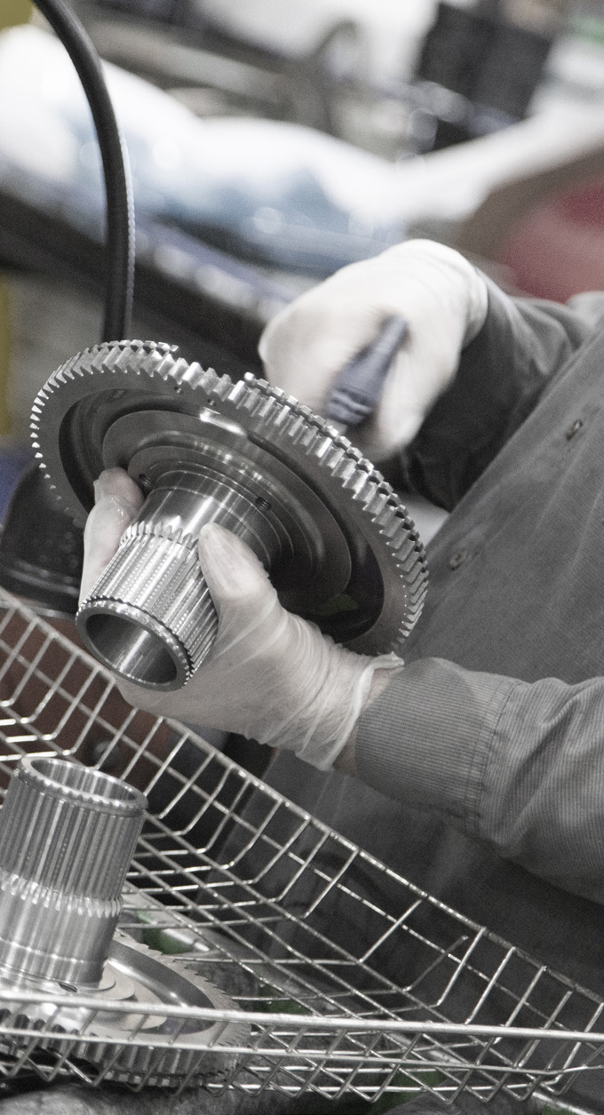 close-up photo of hands assembling a metal gear with wire mesh and tools in the background