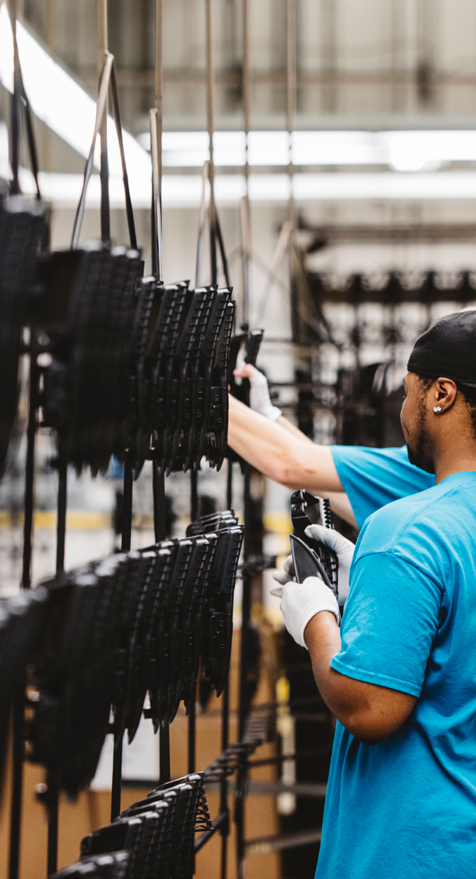 worker in blue shirt operating a production line with black racks in a manufacturing facility