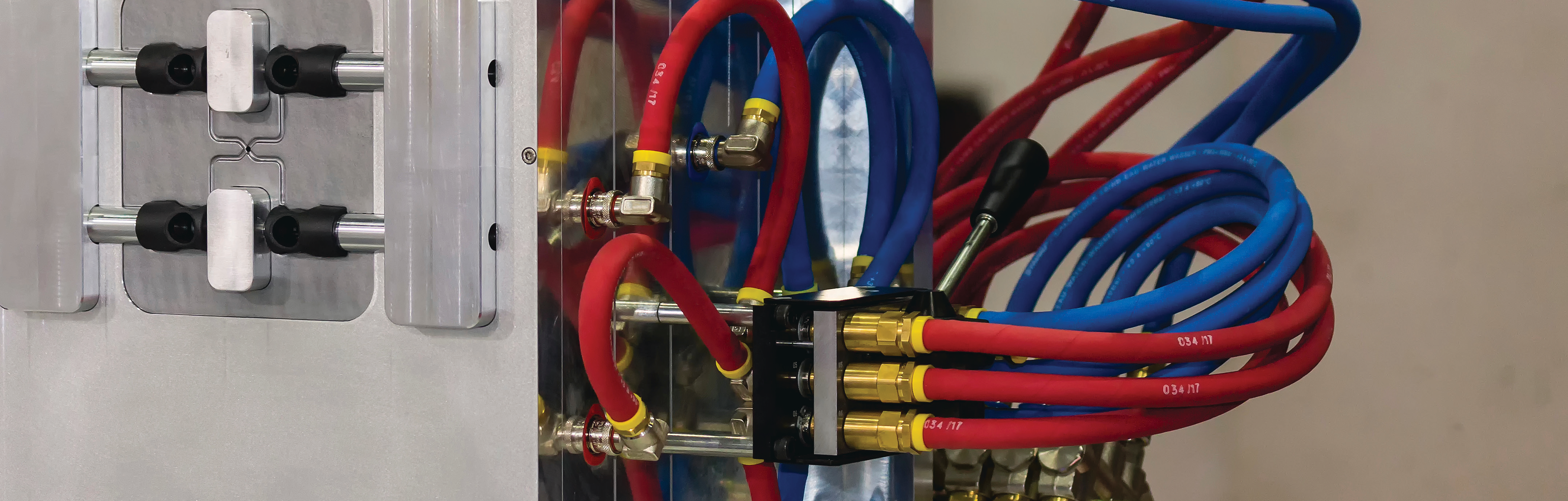 close-up photo of red and blue industrial hoses connected to metal fittings in a factory setting