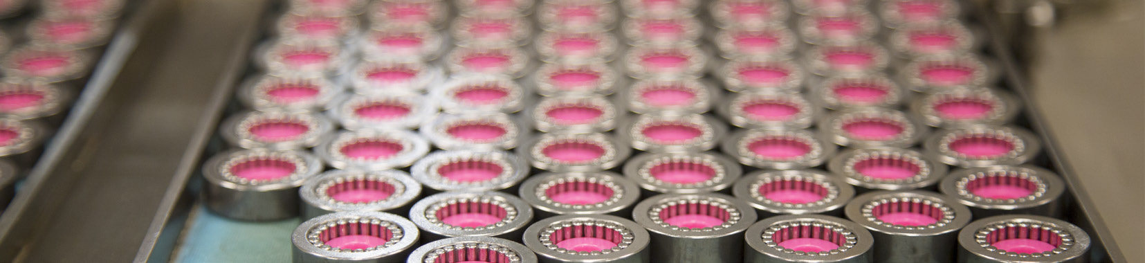 close-up photo of metal bearings arranged in rows on a conveyor belt