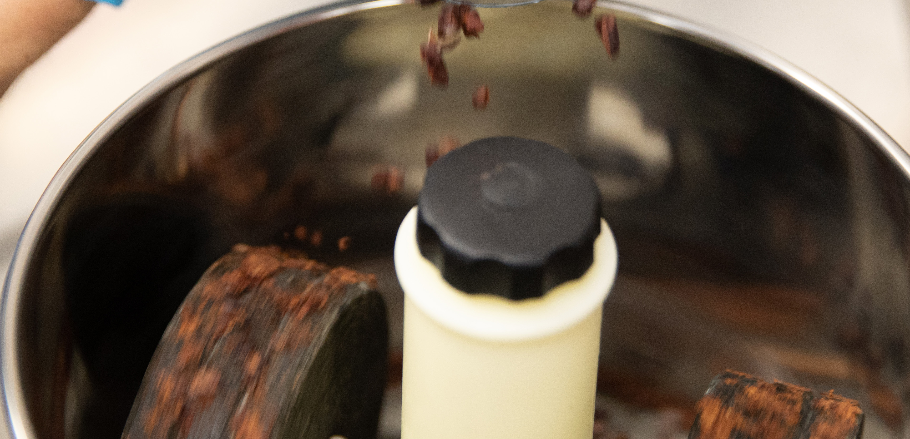 close-up photo of cocoa beans falling into a chocolate processing machine