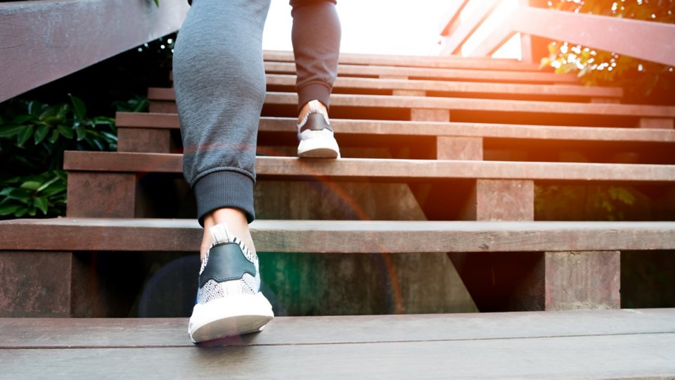 Imagen en primer plano de las piernas y los pies de una persona subiendo una escalera