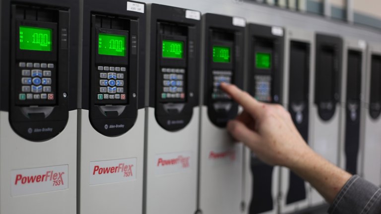 Engineer selects parameters on a PowerFlex 753 variable frequency drive (VFD) keypad. The VFD is one of a line-up of a dozen drives in a row. 