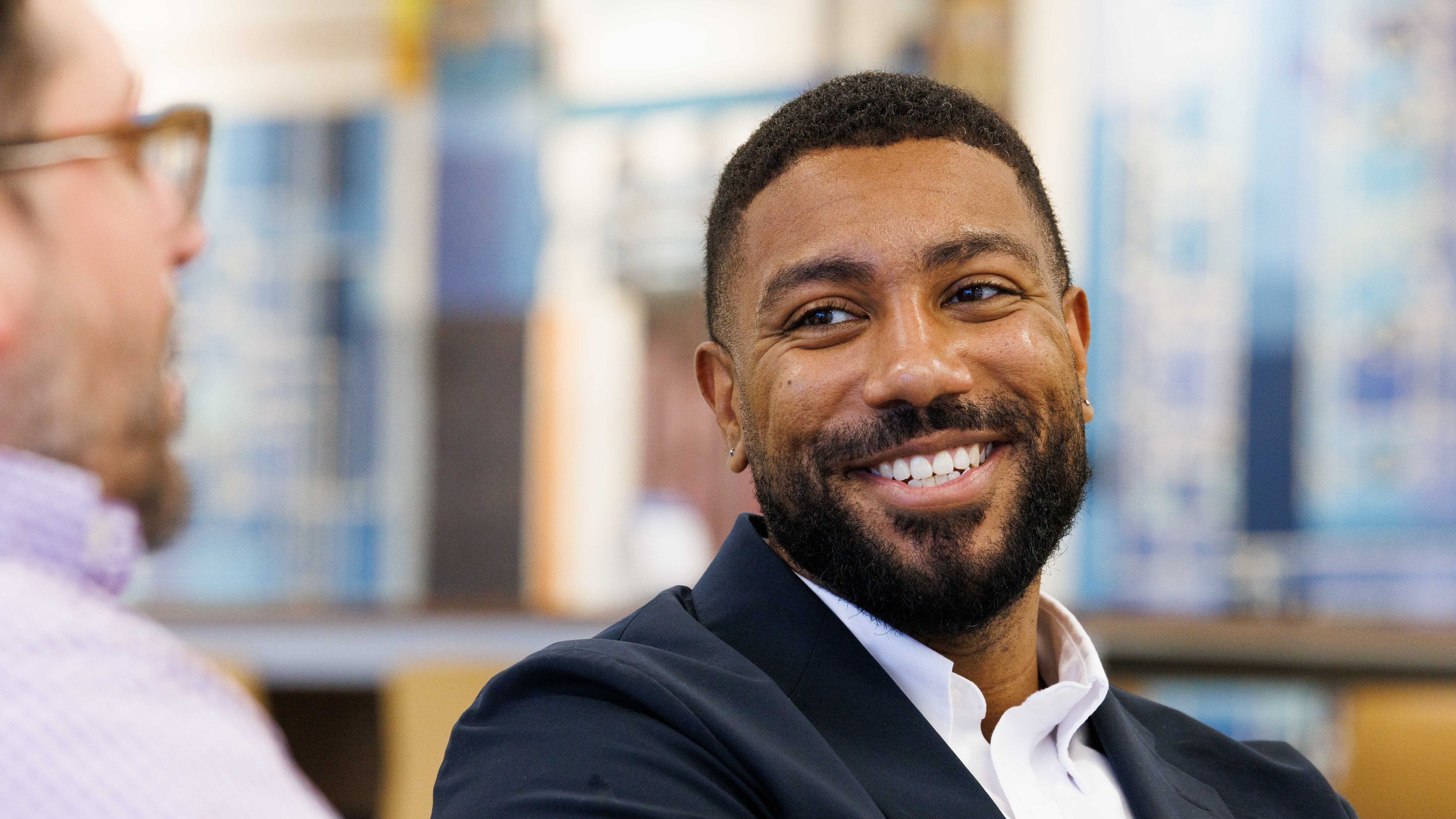 Professional man smiling during a workplace conversation, showcasing diversity, collaboration, and an inclusive company culture.