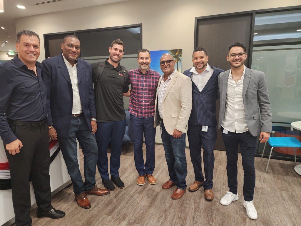 A group of men standing together, smiling for a photo in a professional office setting
