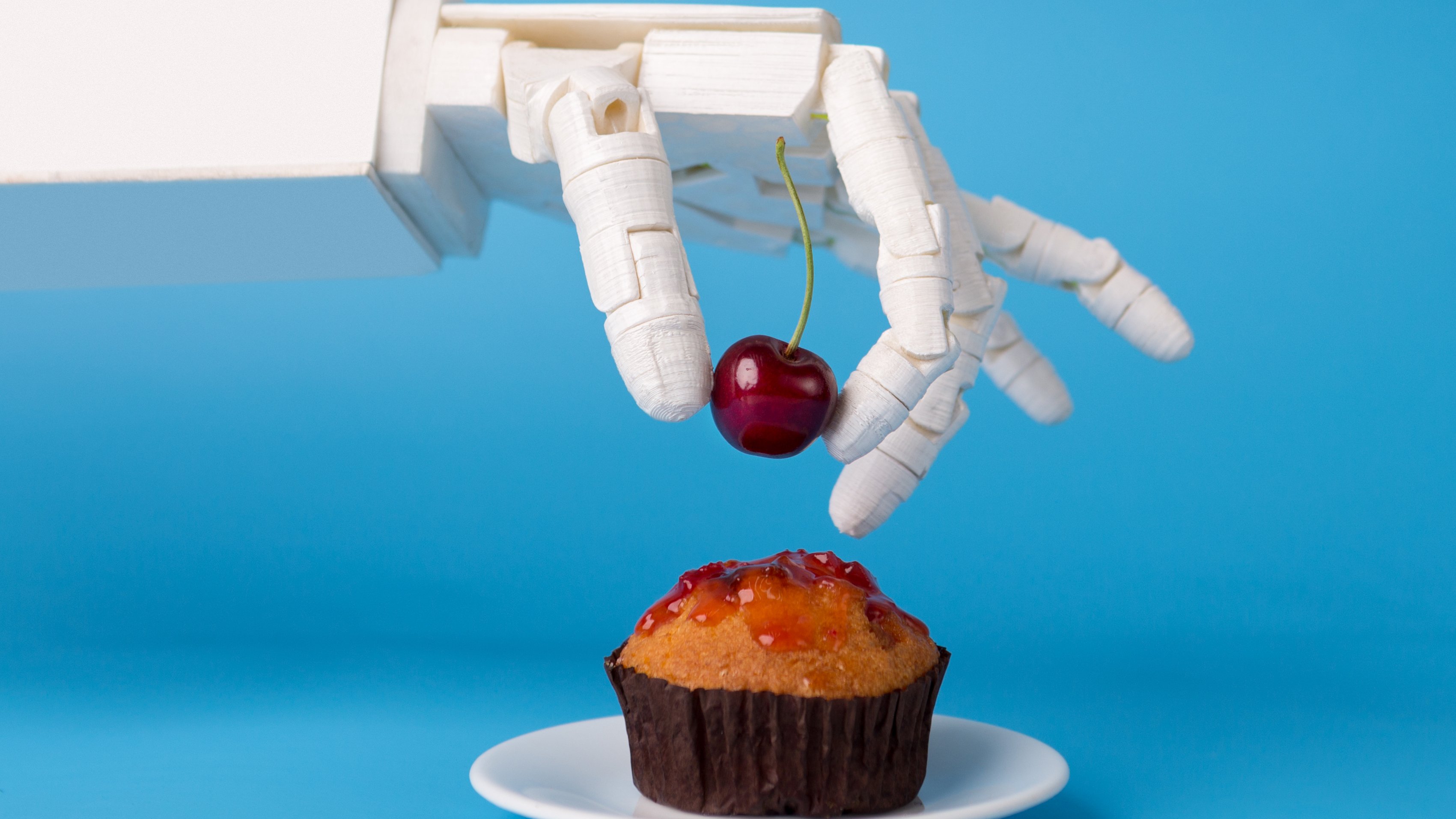 Robotic hand decorating cupcake with cherry