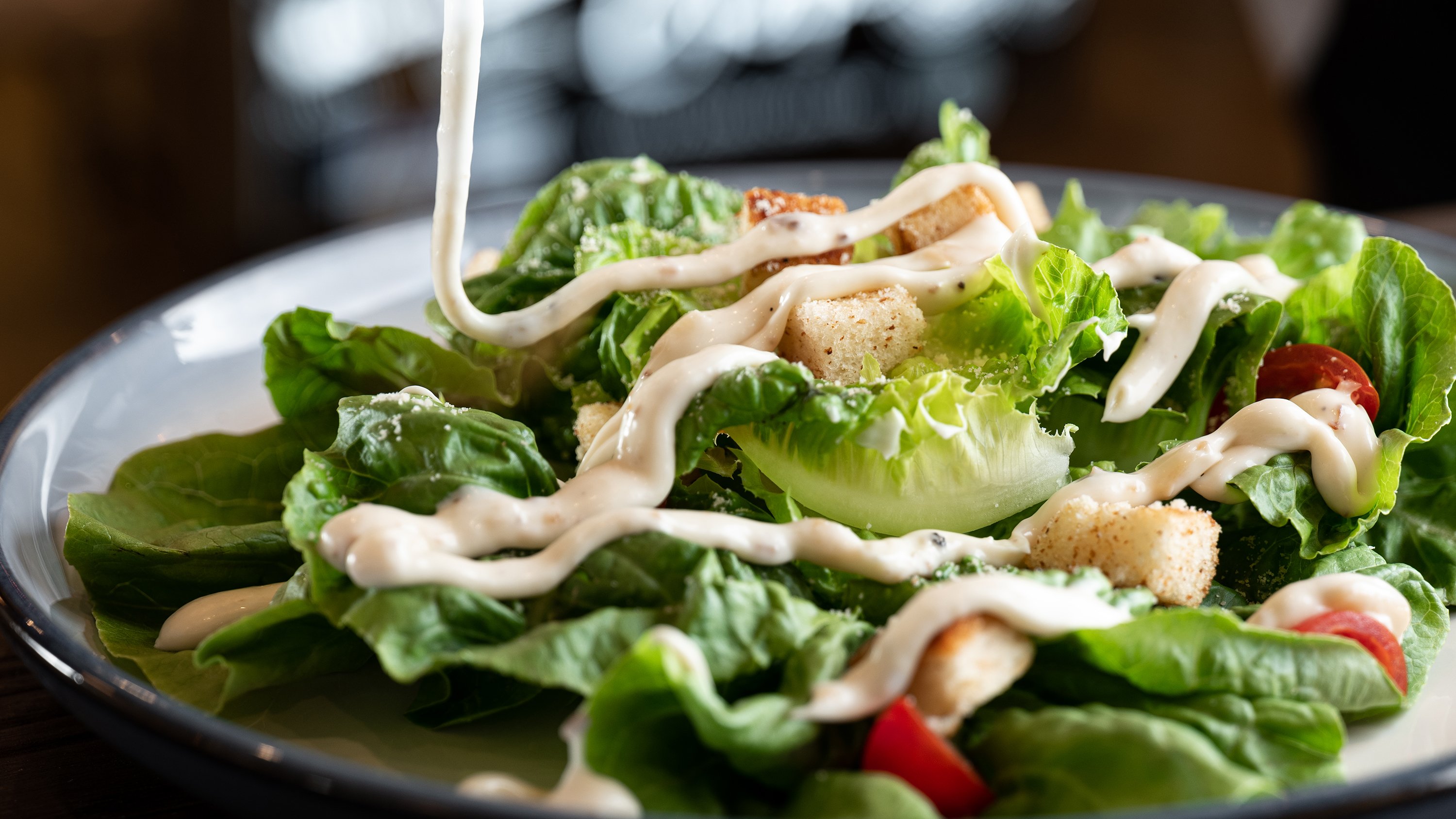 A plate with salad with dressing being poured on from above