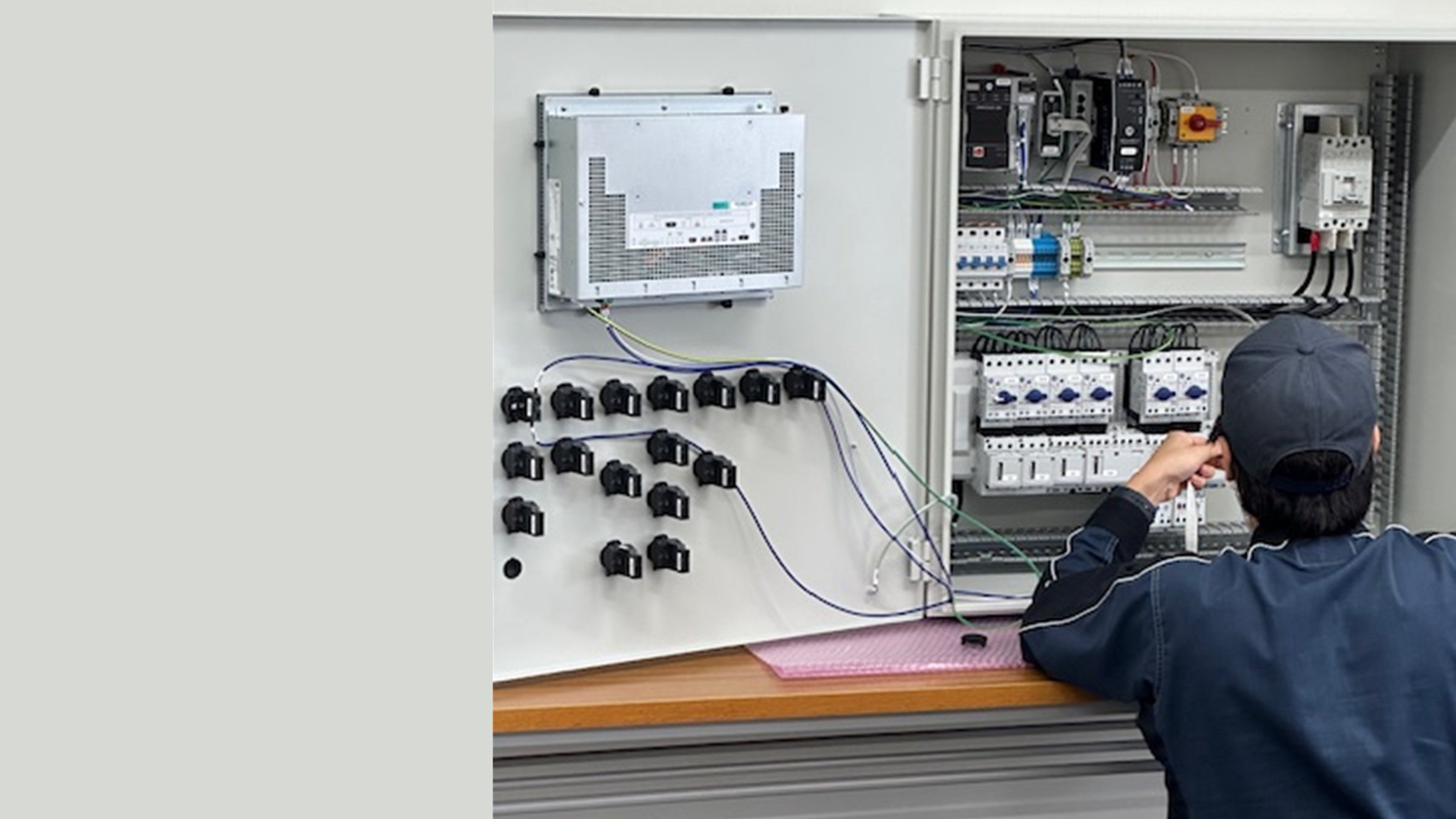 Technician wiring and testing components inside an industrial electrical control panel and automation system.