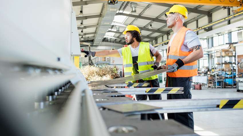 Male worker manufacturing sheet metal on fabrication equipment.