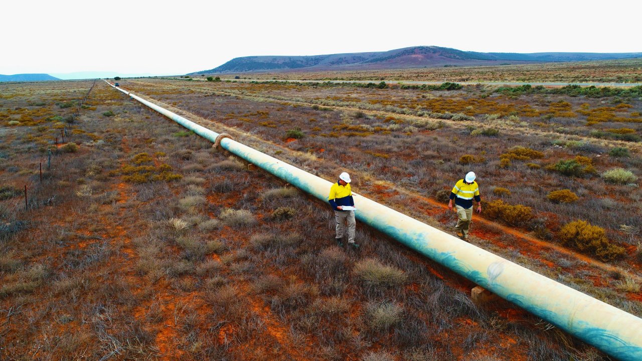 two workers walking by the pipeline