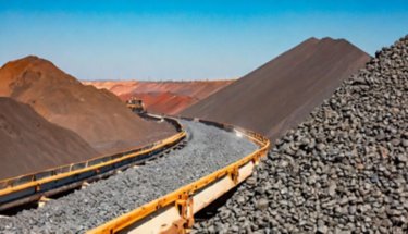 Raw Iron Ore Lumps on a Conveyor Belt in a Mining Site Under Clear Sky