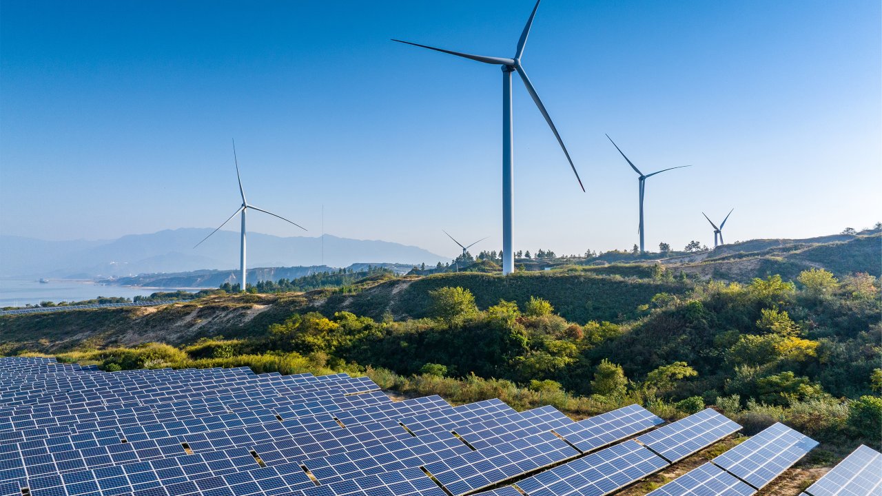 Solar panels and wind power generation equipment with blue sky background.