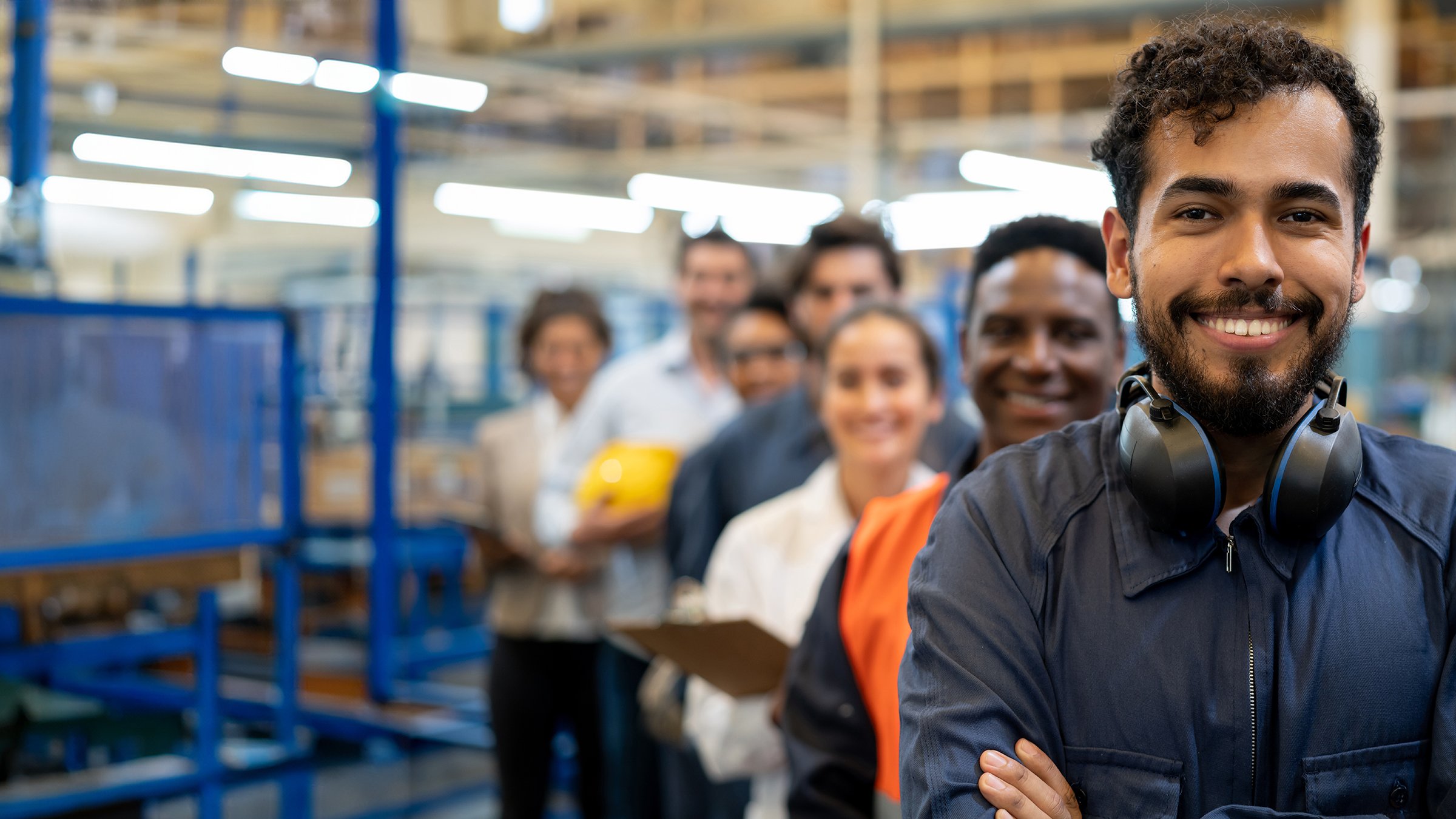 Cheerful hteam of engineers at a factory standing in a row smiling at camera with arms crossed