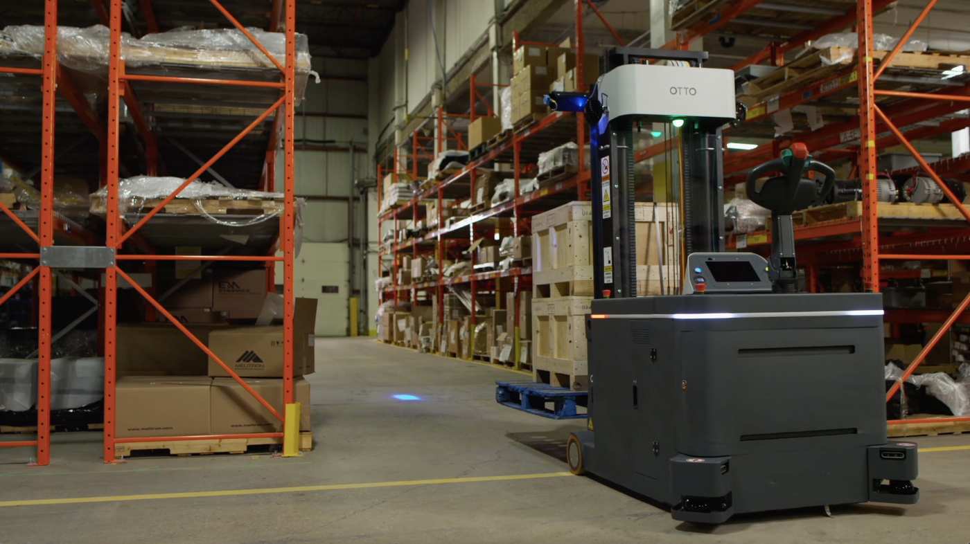 an autonomous forklift moves crates down a warehouse aisle