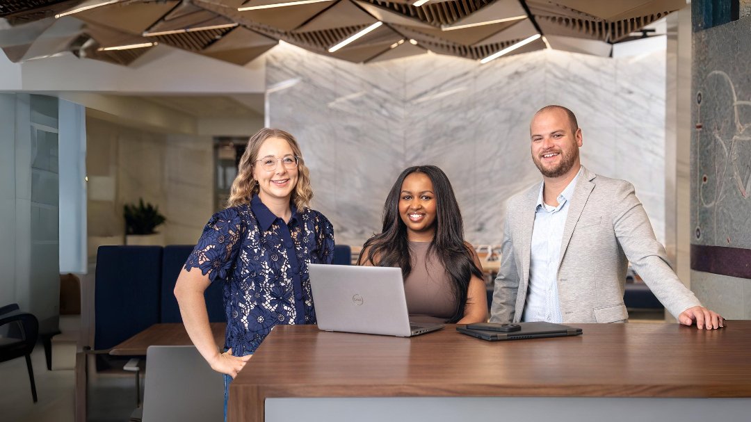 Three Rockwell employees posing with work laptops