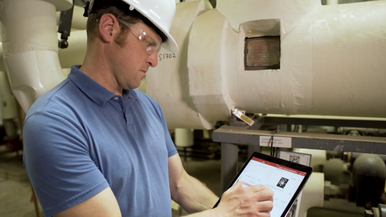 Man in white hard hat and safety goggles uses ScanESC software to lockout equipment before servicing.
